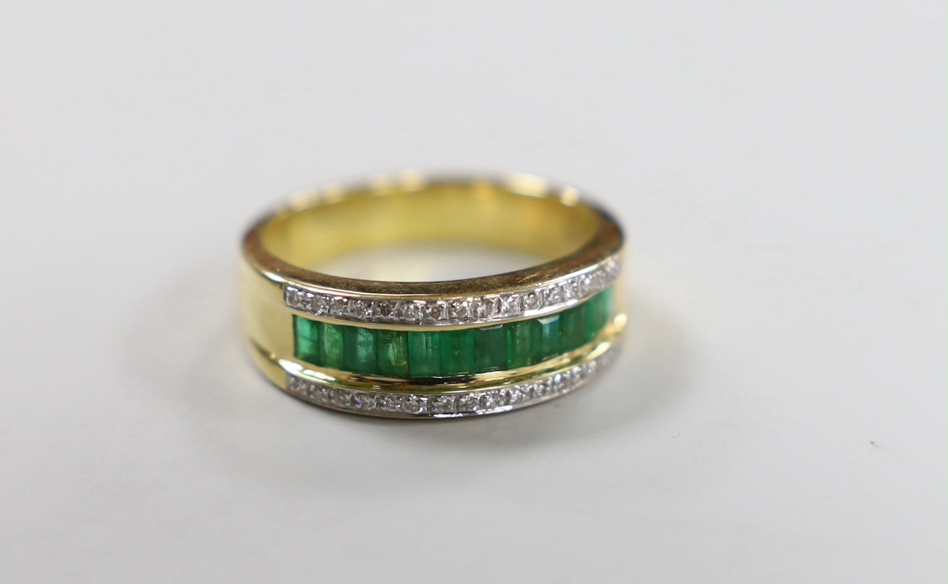A modern 750 yellow metal, emerald and diamond cluster set triple row ring, size P/Q, gross weight 7.1 grams.